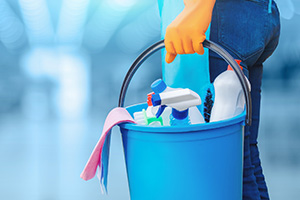 Woman Holding a Bucket With Cleaning Products