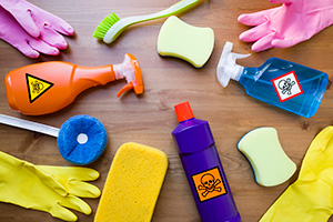 Cleaning Bottles With Toxic Labels Among Cleaning Gloves and Sponges