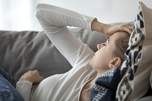 Woman Nursing a Headache on a Sofa