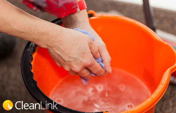 Close-Up of Hands Wringing Cleaning Cloth in a Bucket Simbolizing the Dangers of Quat Binding